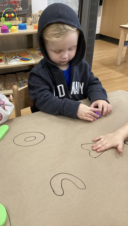 A child sitting and looking at a foam letter in their hands