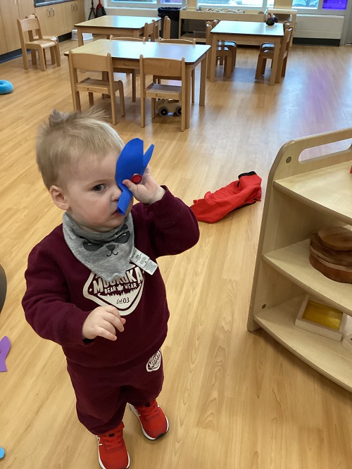 A child holding a blue fish against their face.