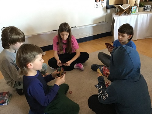 5 School Age 2 children sitting in a circle on the carpet holding cards in their hand and looking at the cards