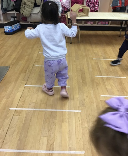 1 Toddler child walking along a path broken up by tape lines
