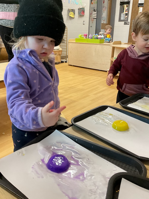 child observing water from ice on her finger