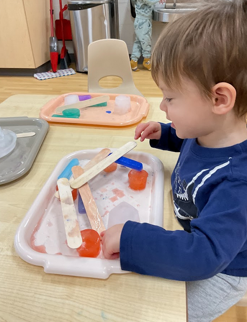 child playing with sticks and ice