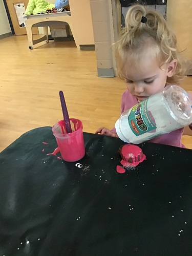 A child putting sparkles on her Diya