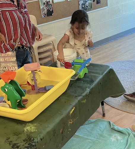 Preschool child pouring water into a balance scale