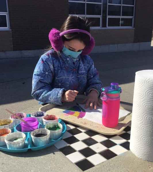 school-age girl painting outside