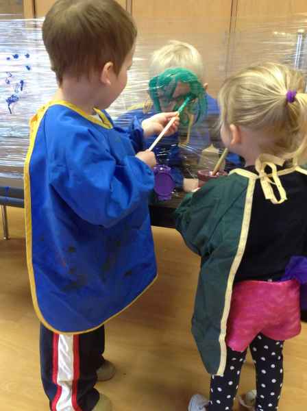 boy painting on a plastic canvas - the other children observe