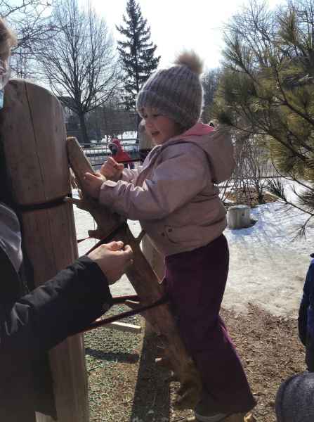 girl climbing a log with educator assistance