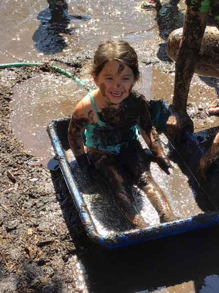 happy girl sitting in a tub of mud