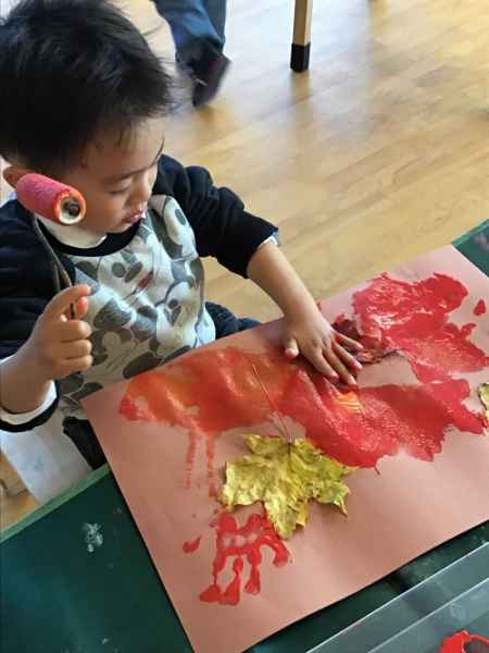child finger painting with leaves