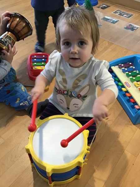 toddler playin a toy drumb