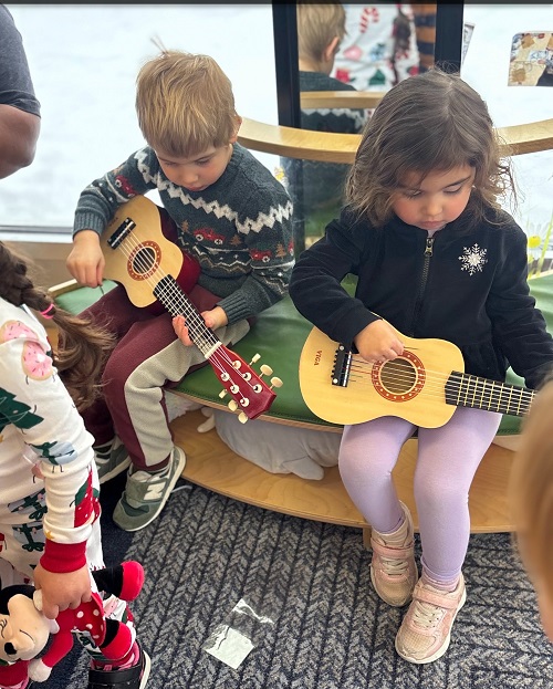 two children sitting playing guitars