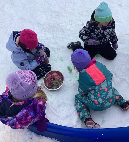 four children in the snow with a bowl full of slushy snow and food colouring