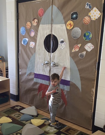 child pointing at rocketship mural painting