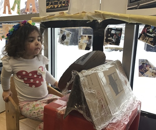 child sitting in a pretend bus made from cardboard