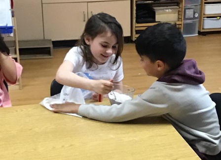 2 children at a table mixing ingredients