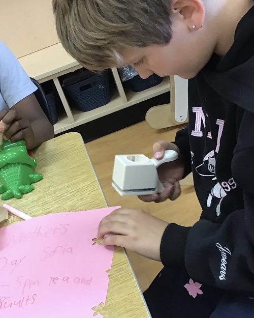 child doing a craft with pink paper