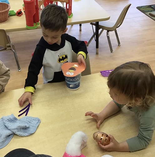 children hold pretend eggs and a bird craft