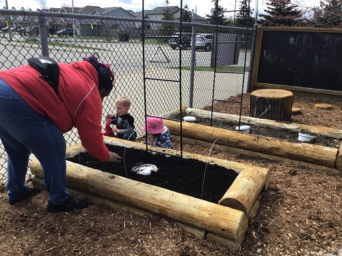 educator and children doing work in the garden bed
