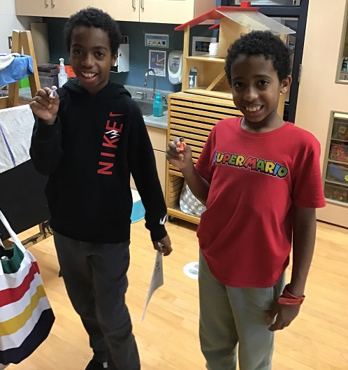 2 children showing game pieces they created