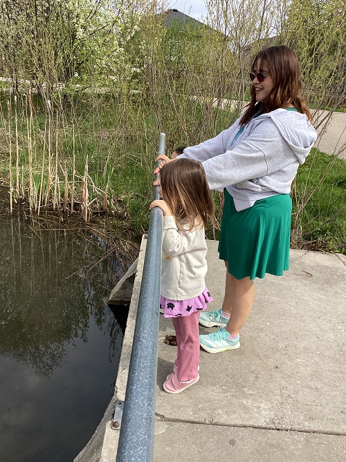 educator and child standing looking at a pond