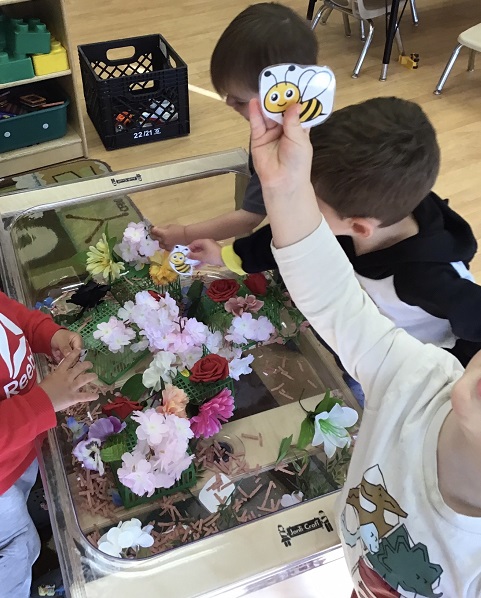 children playing in a sensory bin with flowers
