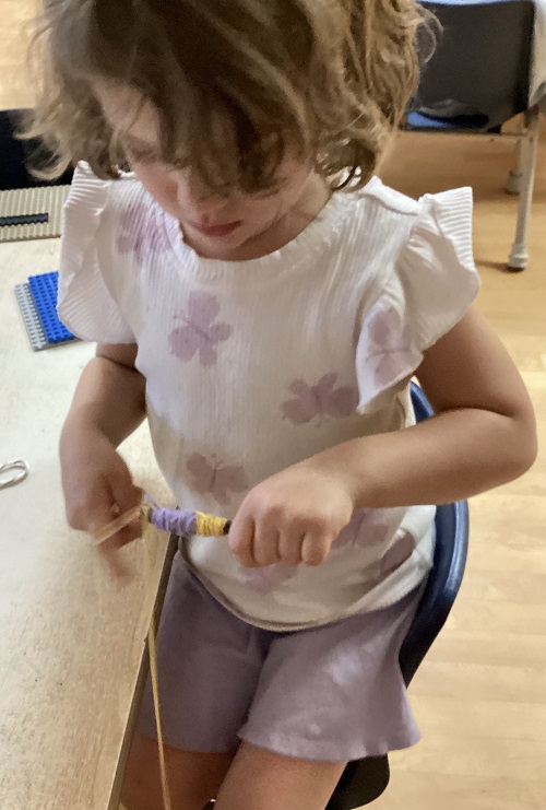 child twisting yarn around a stick