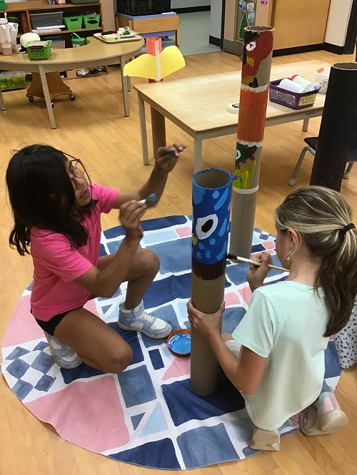 children decorating long cardboard tubes