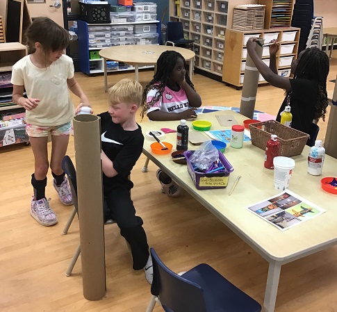 children decorating long cardboard tubes