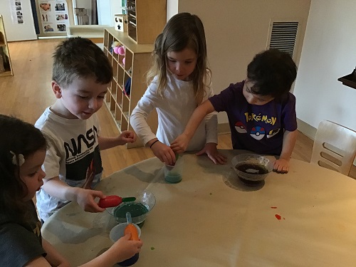 A group of preschoolers are using droppers to try and mix oil and water.