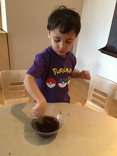 A preschooler is using a dropper to try and mix oil and water.