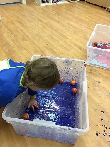 Girl rollong balls covered in paint on paper