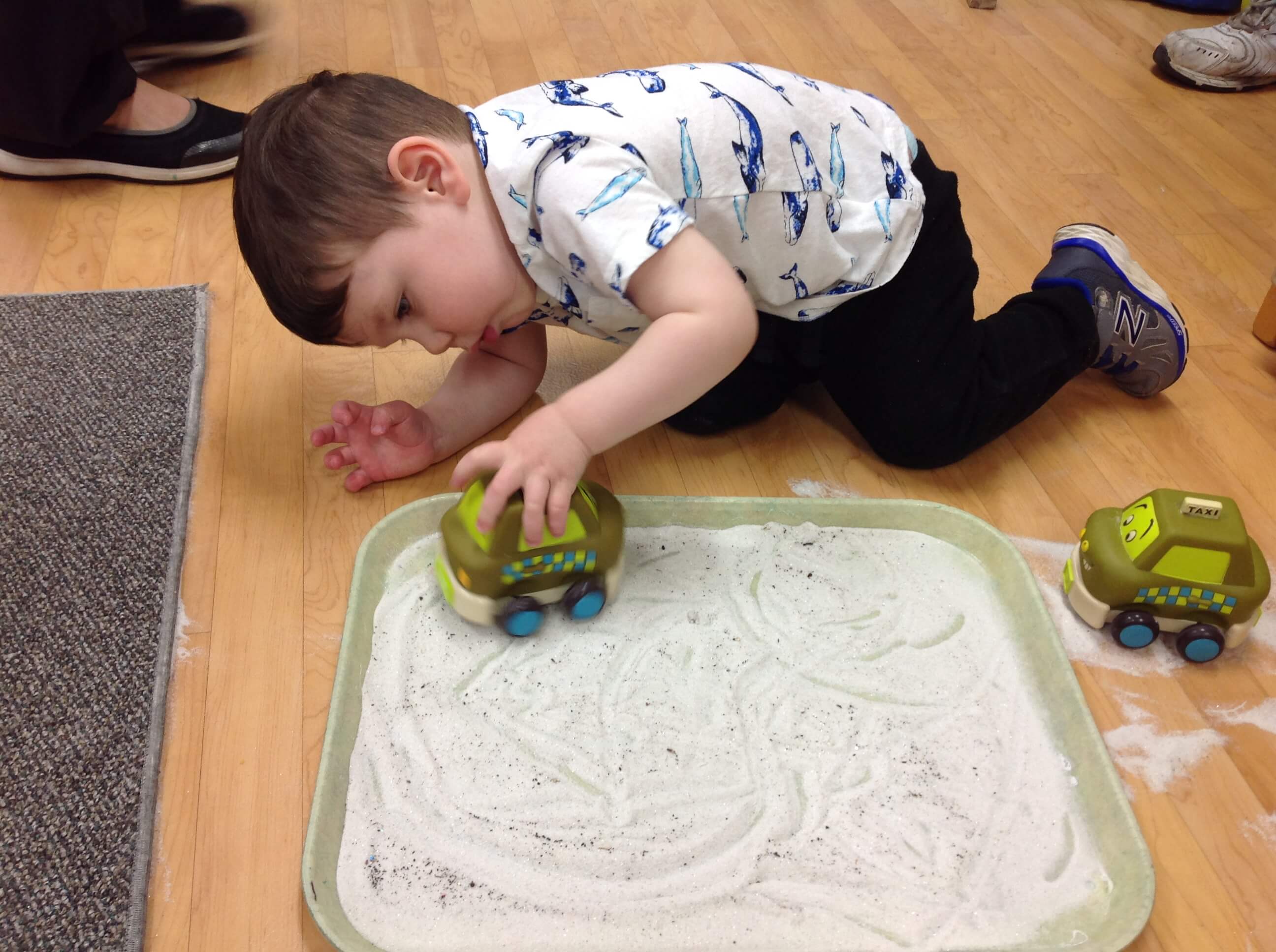boy playing with a car in sand
