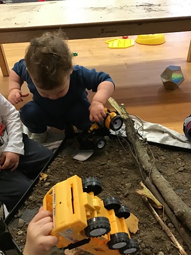 A toddler is driving construction vehicle in the mud.