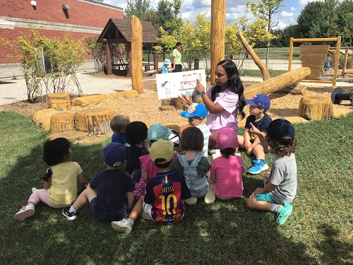 Group of preschool reading story together outside 