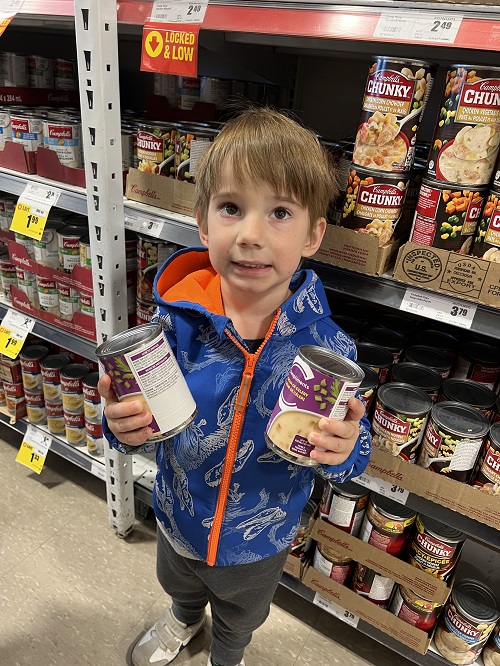 child holding two cans in the grocery store