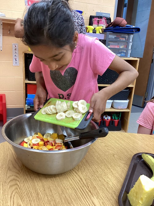 child scraping fruit into the bowl