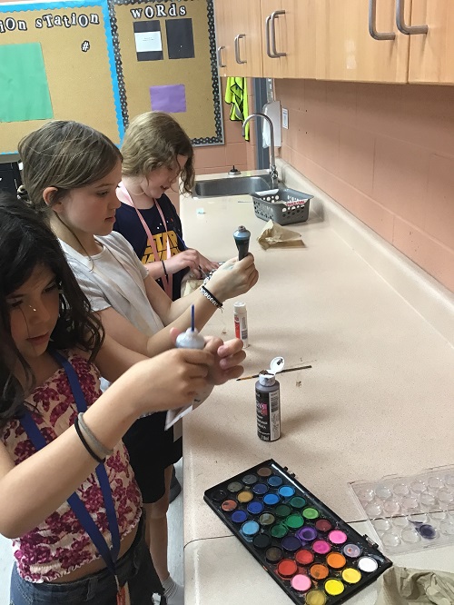 children using loose parts and paint at the counter