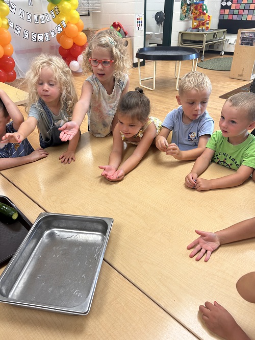 children sitting at the table with a cooking pan in the middle
