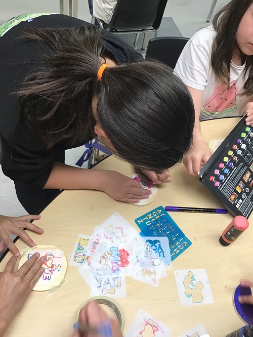 A child working on their coasters using a fabric marker
