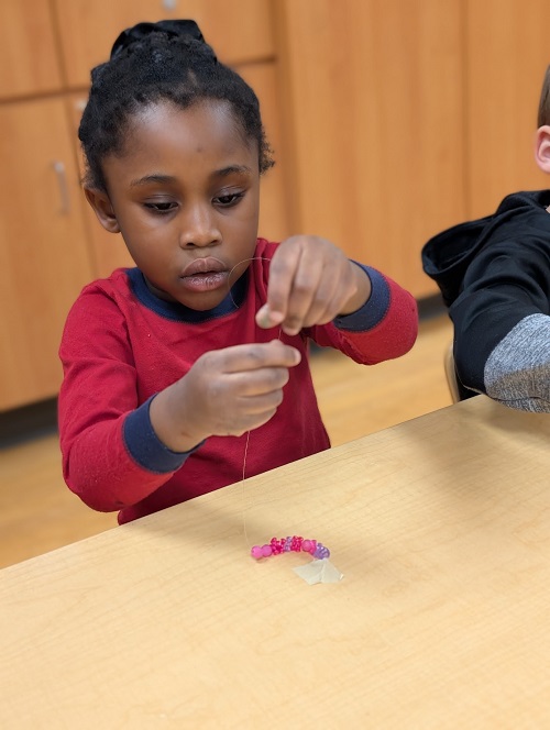 Child placing beads onto a string