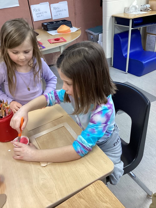 child wrapping yarn around cardboard heart