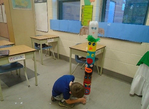 boy assembling children-created totem pole