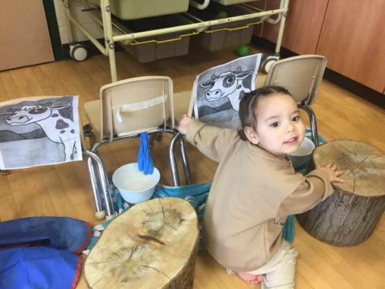 child sitting on the floor beside some wood stumps