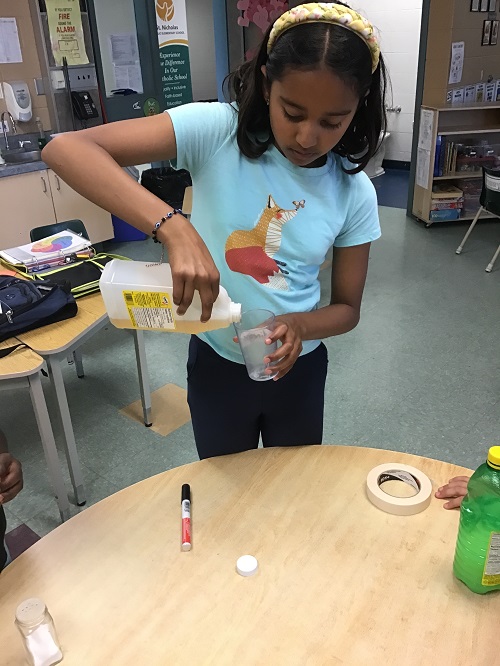 Child pouring apple cider vinegar into a cup