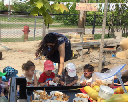 Educator handing our snack to group of children during their picnic.