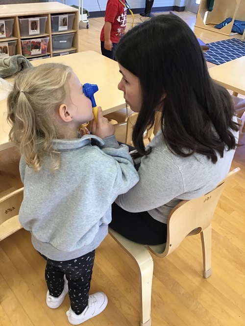 Child pretending to give a checkup to an educator.