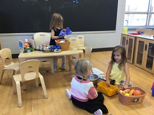 Children pretending to make meals with dramatic play materials.