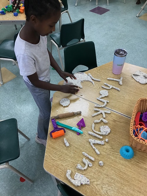 Child showing the playdough created word "Thanksgiving."