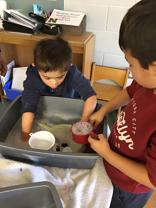 Children placing hands in water bin.