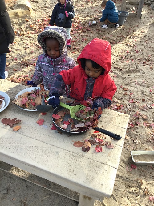 Children using their imagination, pretending to cook with leaves, pots and pans.